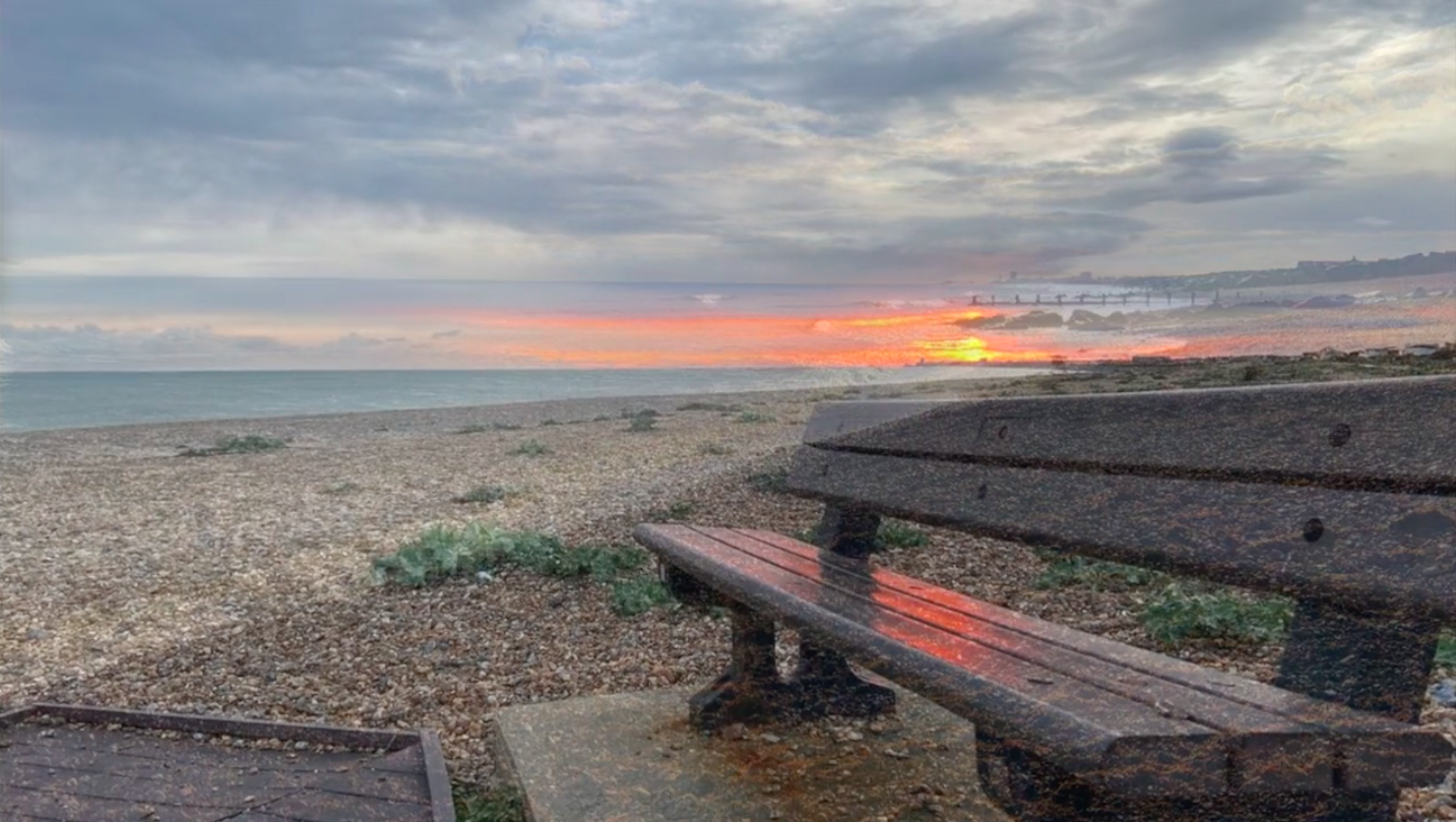 Sunset on the sea with bench and pebbles